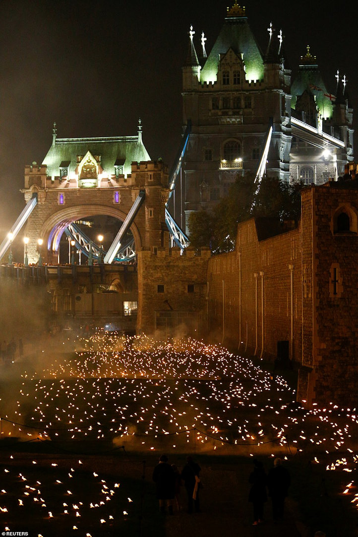 Tower Bridge mysteriously lit overlooking the moat filled with lit torches