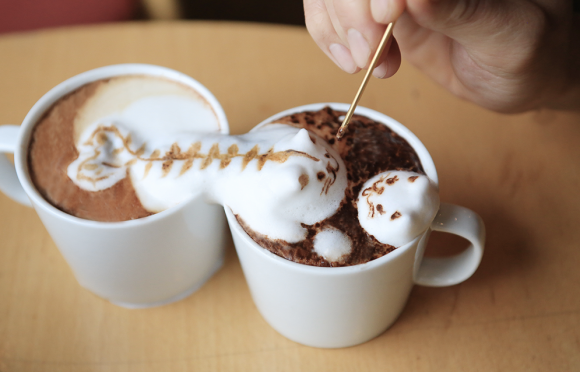Adding finishing touches to frothy coffee cat
